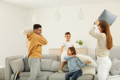 Photo of Happy family having pillow fight in living room