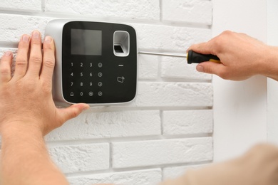 Photo of Male technician installing security alarm system indoors, closeup