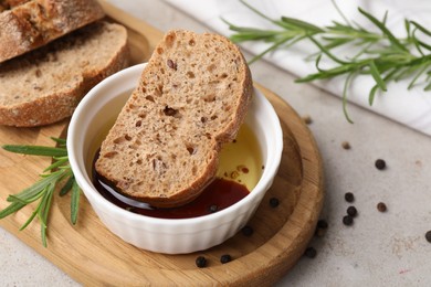 Bowl of organic balsamic vinegar with oil served with spices and bread slices on beige table, closeup