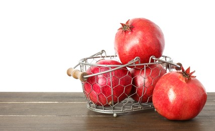 Photo of Fresh pomegranates in basket on wooden table against white background