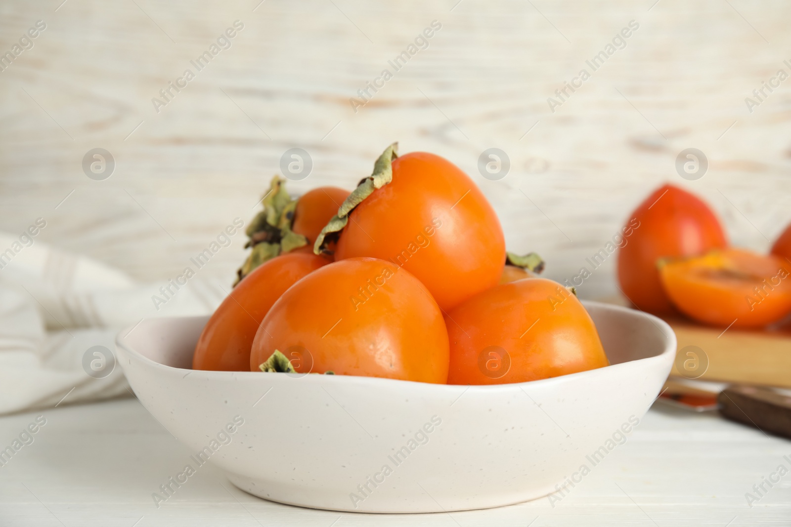 Photo of Delicious fresh persimmons on white table, closeup