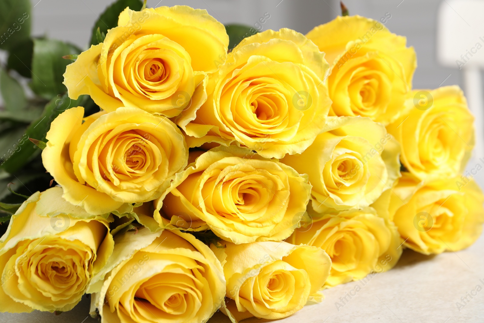 Photo of Beautiful bouquet of yellow roses on light grey table, closeup