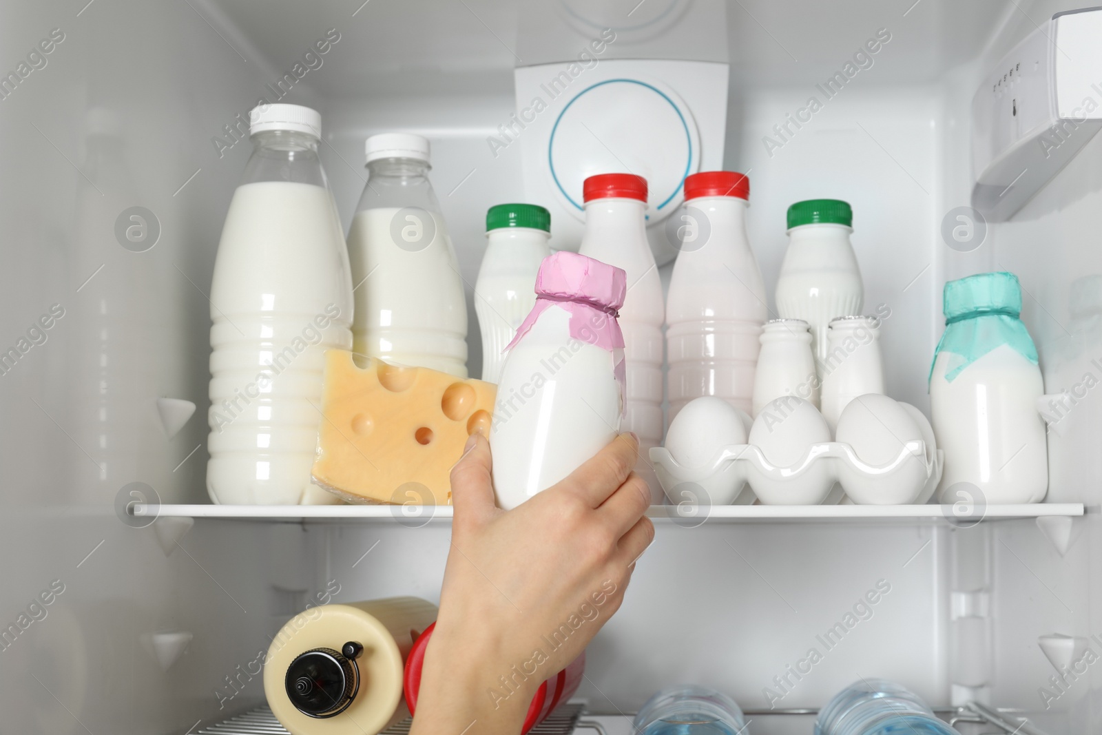 Photo of Woman taking bottle of yogurt from refrigerator, closeup