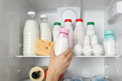 Woman taking bottle of yogurt from refrigerator, closeup