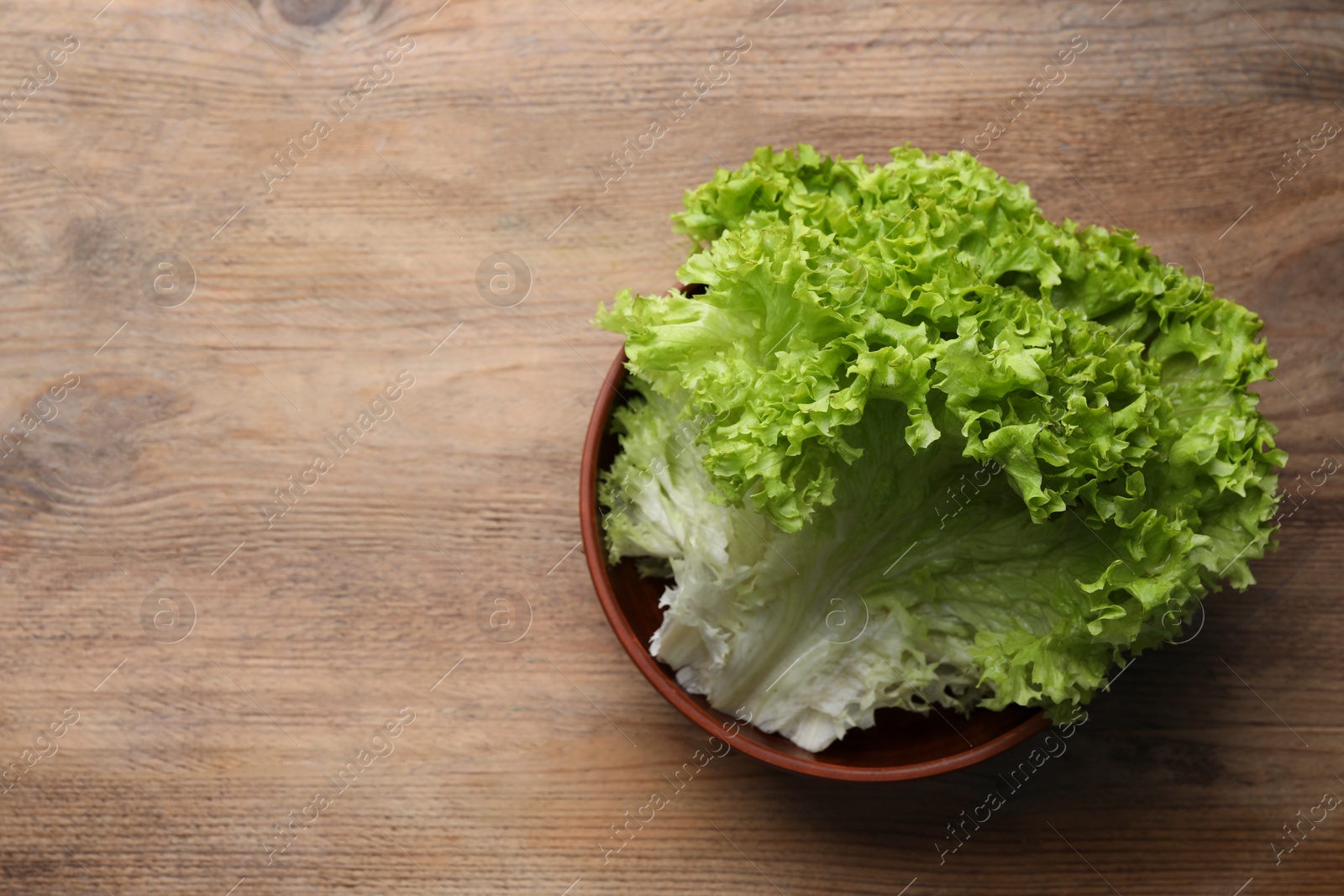 Photo of Fresh lettuce on wooden table, top view and space for text