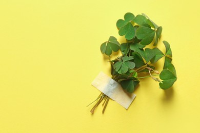Photo of Bunch of green clover with tape on yellow background. Space for text