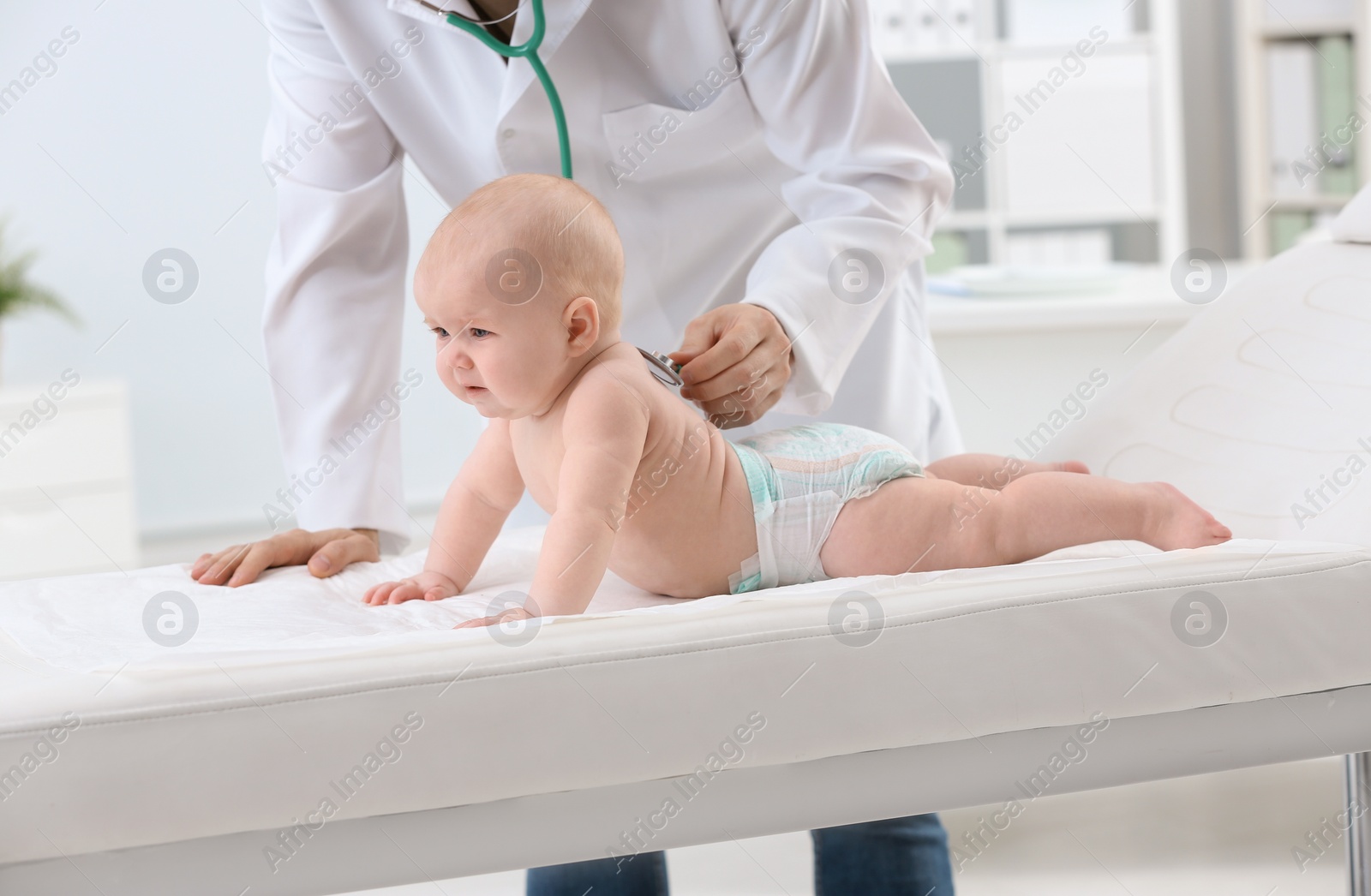 Photo of Children's doctor examining baby with stethoscope in hospital