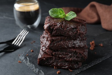 Photo of Delicious chocolate brownies with fresh mint served on black table, closeup