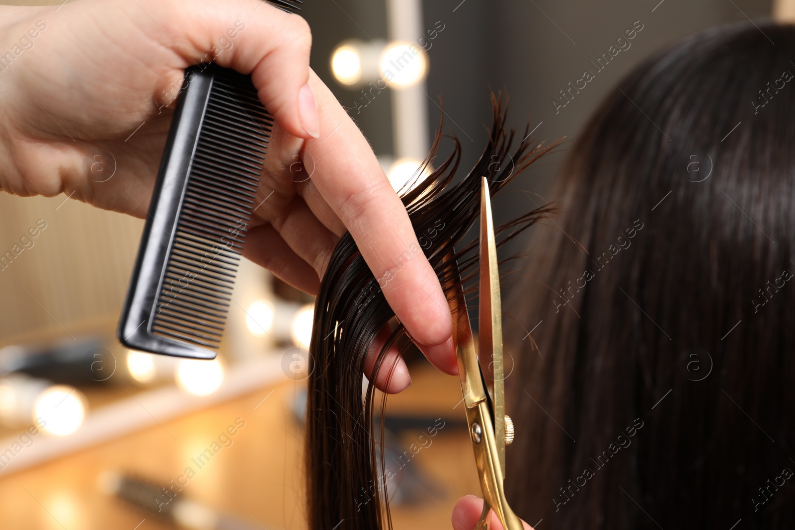 Photo of Hairdresser cutting client's hair with scissors in salon, closeup