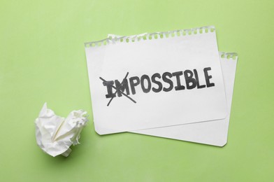 Photo of Motivation concept. Paper with changed word from Impossible into Possible by crossing over letters I and M on light green background, top view