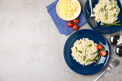 Photo of Delicious risotto with asparagus on grey table, flat lay. Space for text