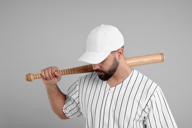 Photo of Man in stylish white baseball cap holding bat on light grey background