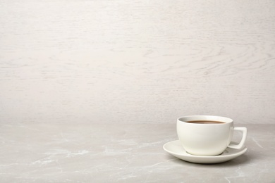 Photo of White ceramic cup with hot aromatic coffee on table