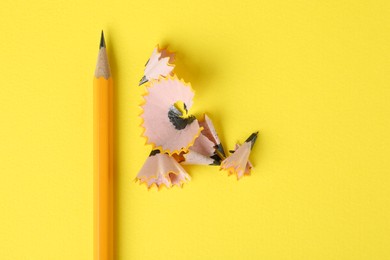 Graphite pencil and shavings on yellow background, top view and space for text. Macro photo