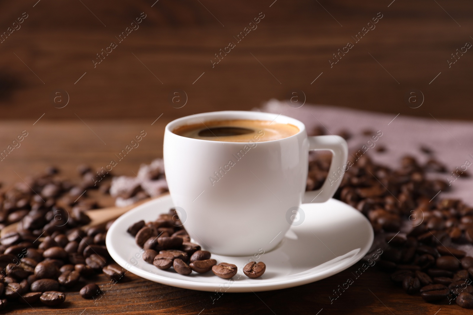 Photo of Cup of hot aromatic coffee and roasted beans on wooden table, closeup