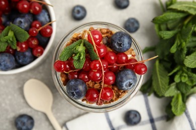 Photo of Delicious yogurt parfait with fresh berries and mint on light grey table, flat lay