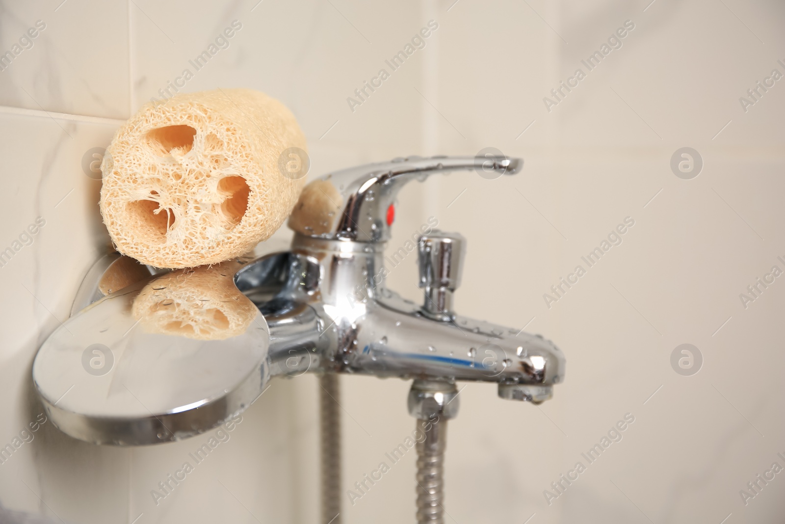 Photo of Natural loofah sponge on faucet in bathroom