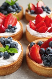 Delicious sweet pastries with berries on grey table, closeup