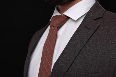 Businessman in suit and necktie on black background, closeup