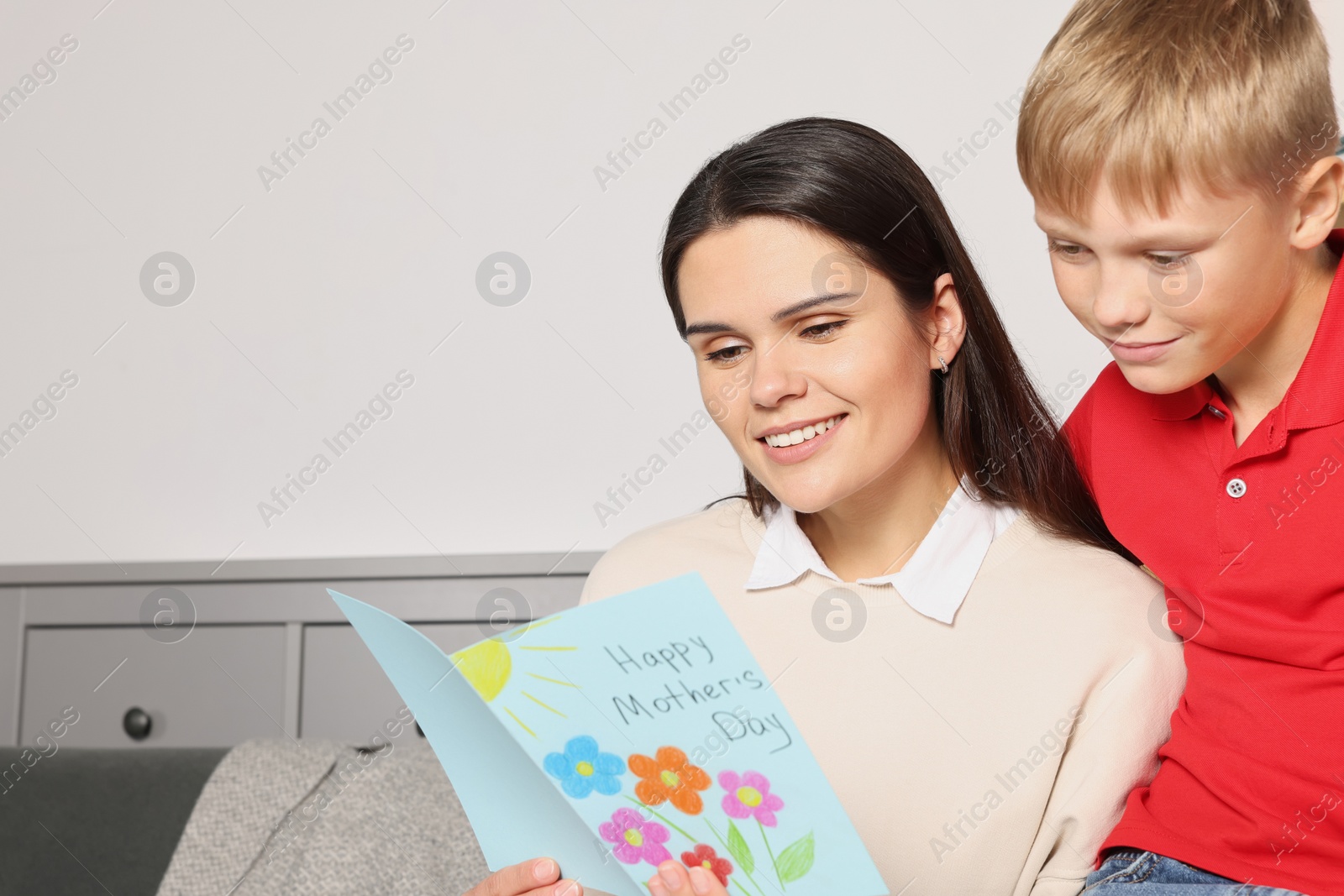 Photo of Happy woman receiving greeting card from her son at home