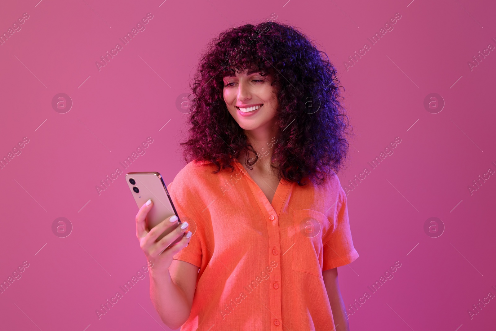 Photo of Woman sending message via smartphone on pink background