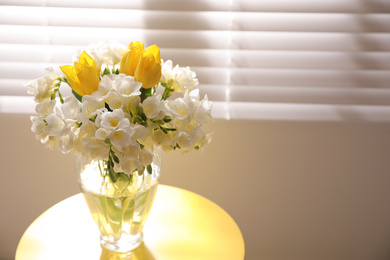 Photo of Beautiful bouquet with fresh freesia flowers in vase on table near window. Space for text