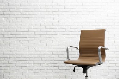 Photo of Comfortable office chair near white brick wall. Space for text