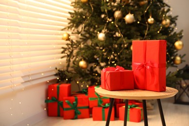 Beautifully wrapped Christmas gifts on wooden table in living room, space for text