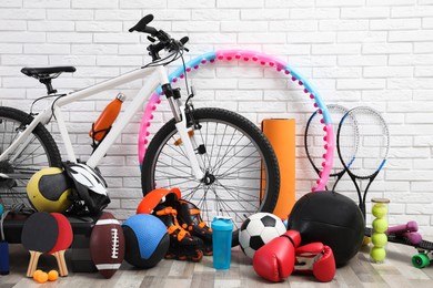 Photo of Bicycle and different sport equipment near white brick wall