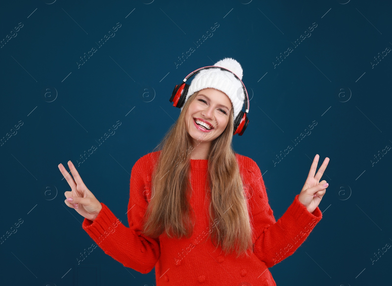 Photo of Young woman listening to music with headphones on dark blue background