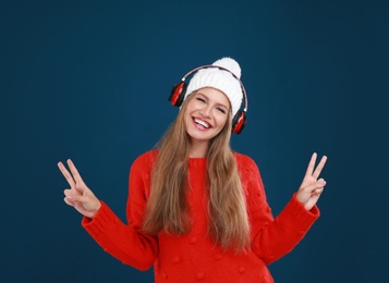 Photo of Young woman listening to music with headphones on dark blue background