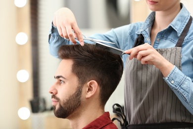 Barber making stylish haircut with professional scissors in beauty salon