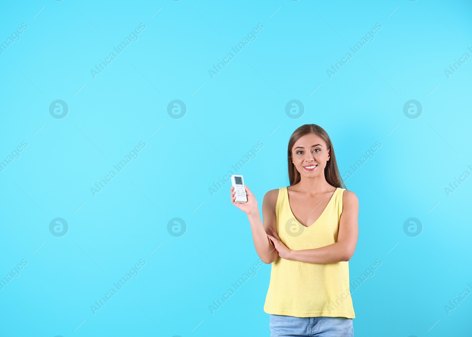 Photo of Young woman with air conditioner remote on color background, copy space text