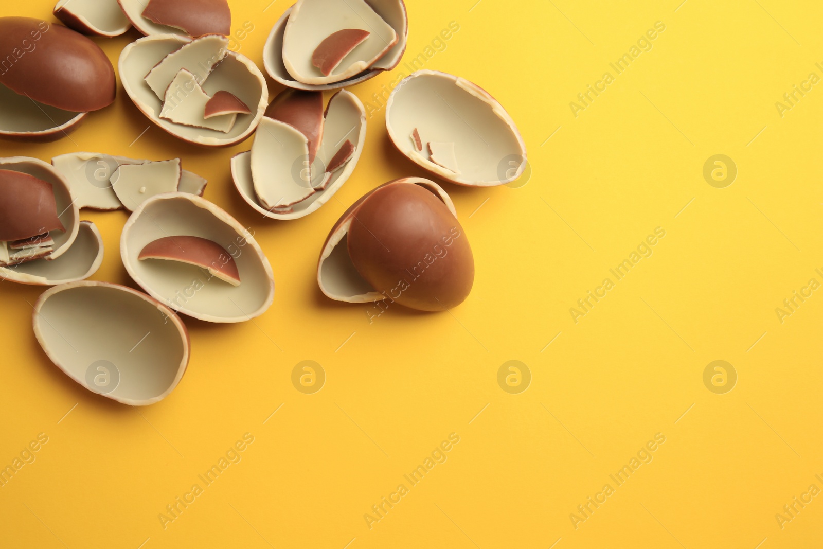 Photo of Sveti Vlas, Bulgaria - July 3, 2023: Broken halves of Kinder Surprise Eggs on yellow background, flat lay. Space for text