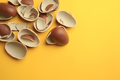 Sveti Vlas, Bulgaria - July 3, 2023: Broken halves of Kinder Surprise Eggs on yellow background, flat lay. Space for text