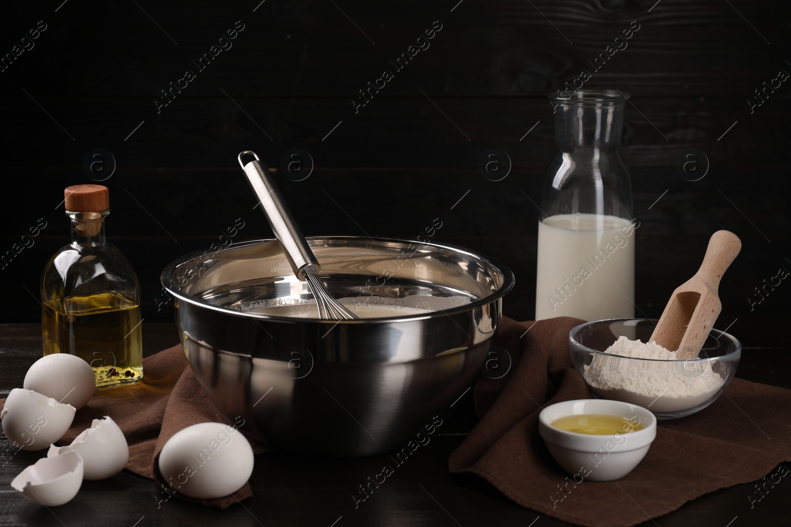 Photo of Composition with whisk and dough in bowl on wooden table