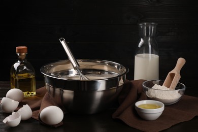 Photo of Composition with whisk and dough in bowl on wooden table