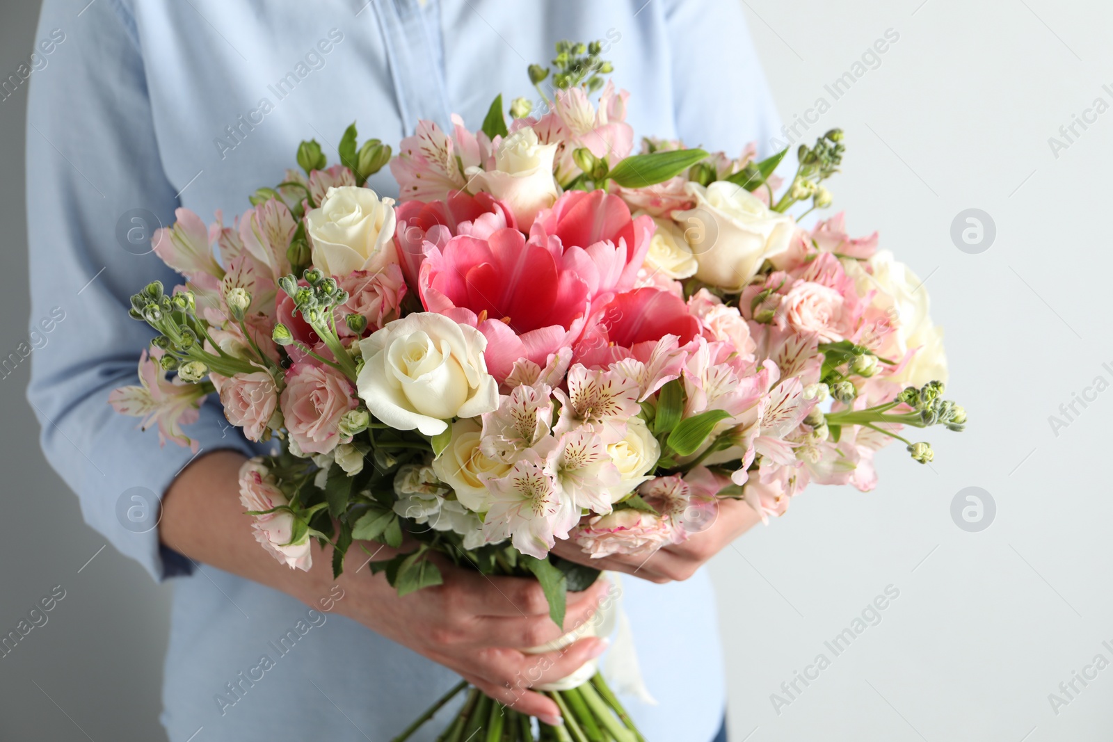 Photo of Woman with beautiful bouquet of fresh flowers on light background, closeup
