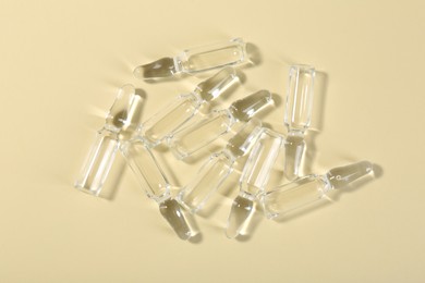 Photo of Glass ampoules with liquid on beige background, top view