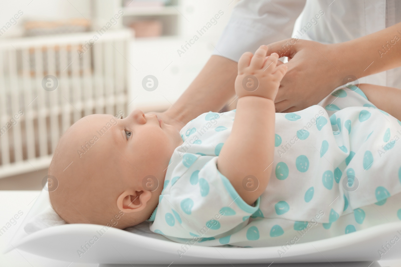 Photo of Doctor weighting baby on scales in light room