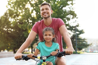 Photo of Happy father with daughter riding bicycle in city