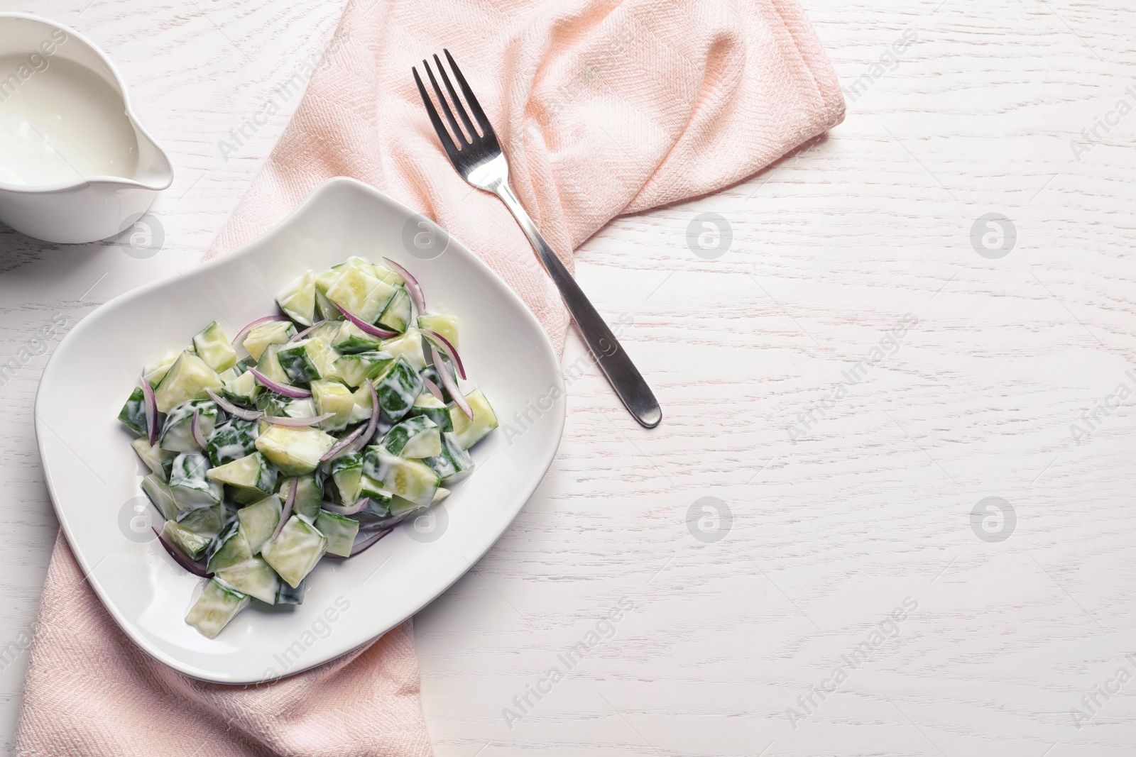 Photo of Flat lay composition with plate of creamy cucumber salad and space for text on wooden table