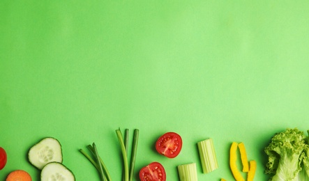 Photo of Flat lay composition with fresh salad ingredients on green background, space for text