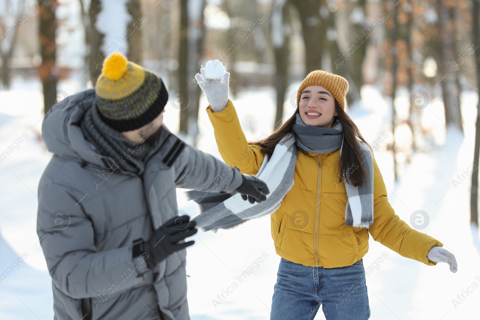 Photo of Happy couple playing snowballs on winter day outdoors