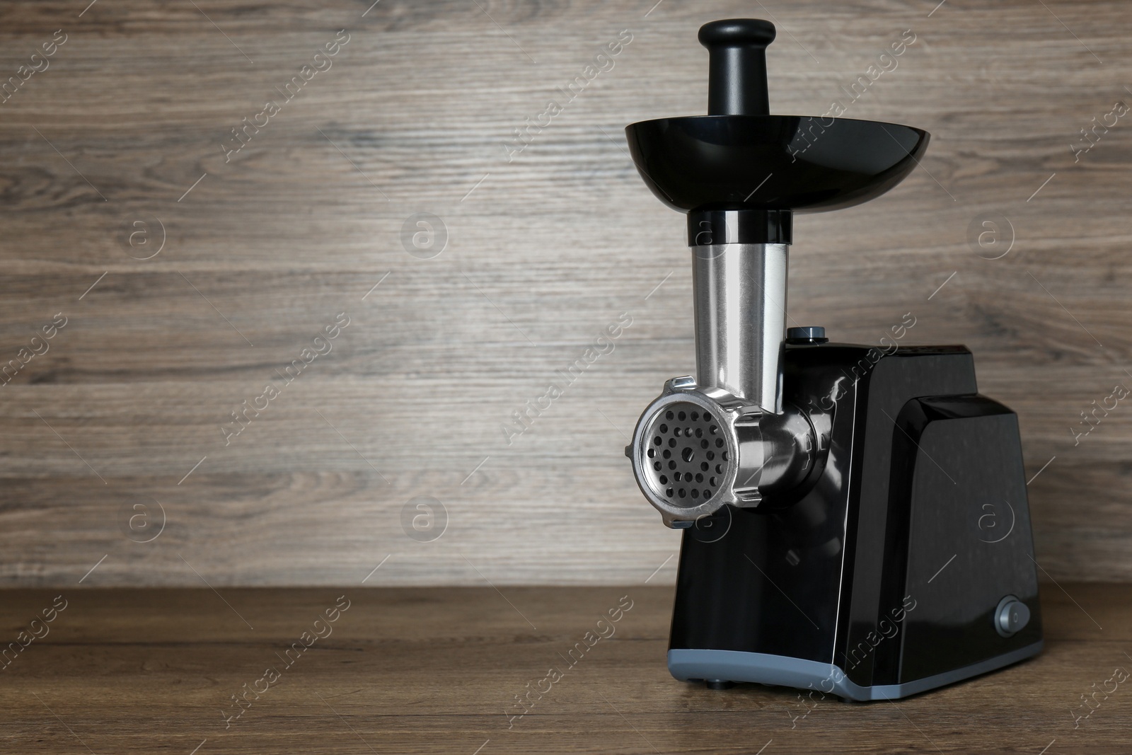 Photo of Modern electric meat grinder on wooden table. Space for text