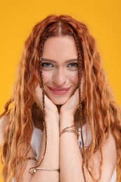 Photo of Beautiful young hippie woman on orange background, closeup