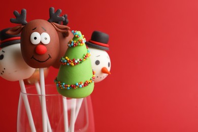 Delicious Christmas themed cake pops on red background, closeup. Space for text