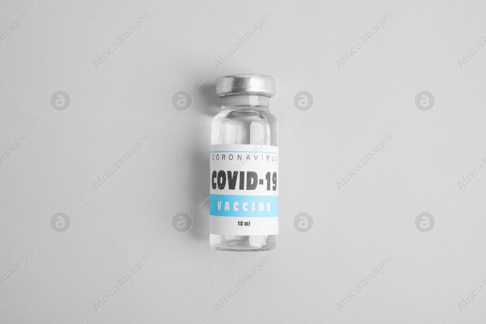 Photo of Vial with coronavirus vaccine on light background, top view