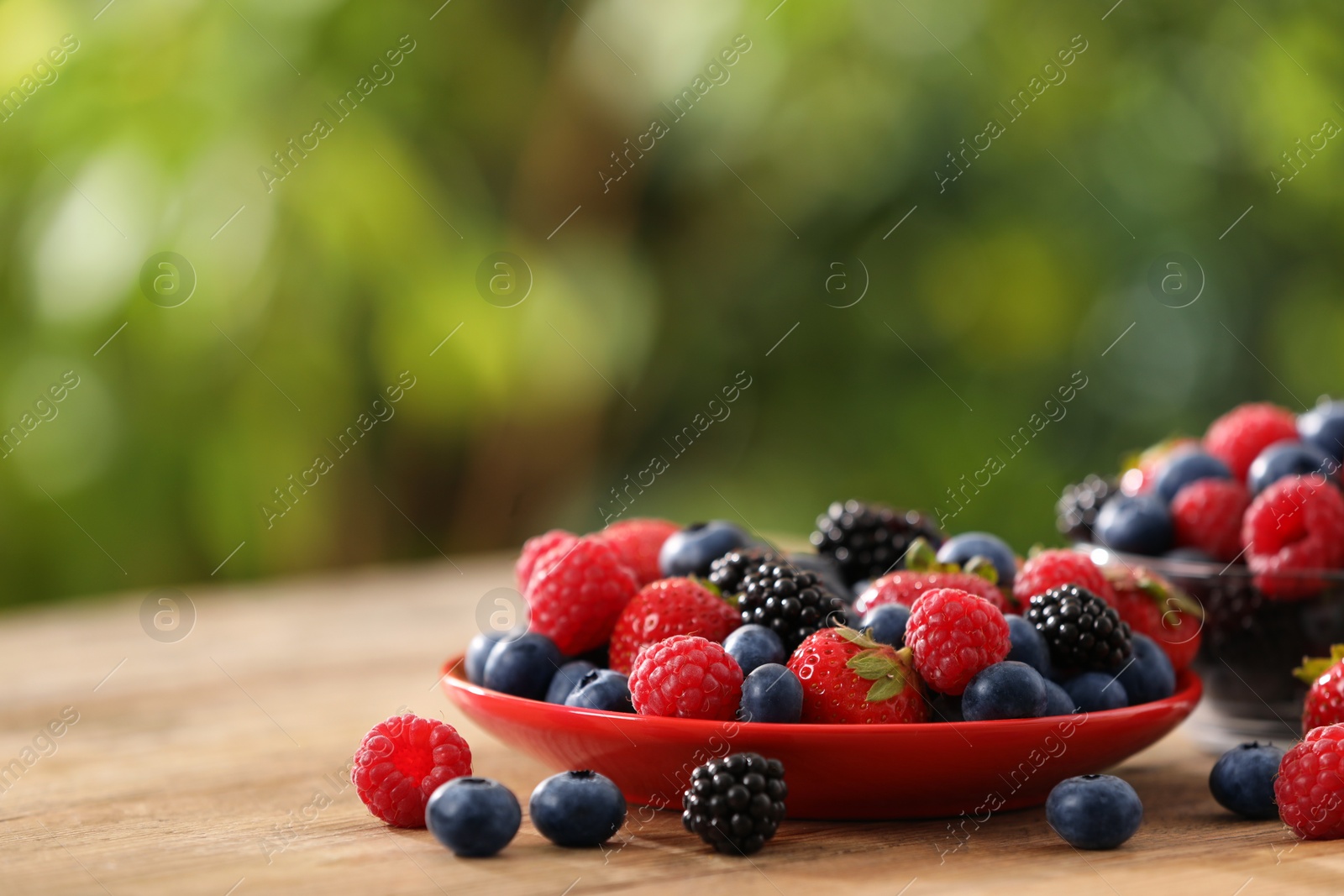 Different fresh ripe berries on wooden table outdoors, space for text Photo of Different fresh ripe berries on wooden table outdoors, space for text