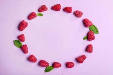 Frame made of tasty raspberries and leaves on lilac background, top view with space for text